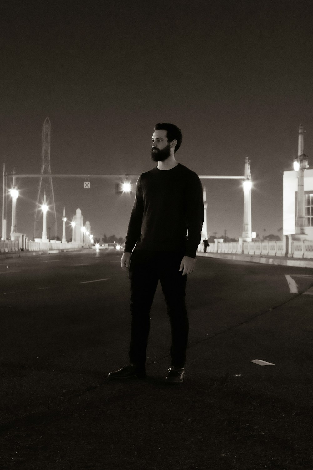 man in black sweater standing on road during night time