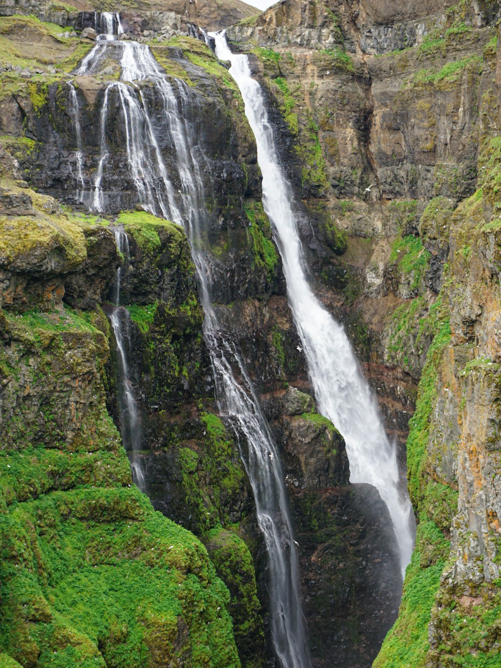 waterfalls on green grass covered hill during daytime