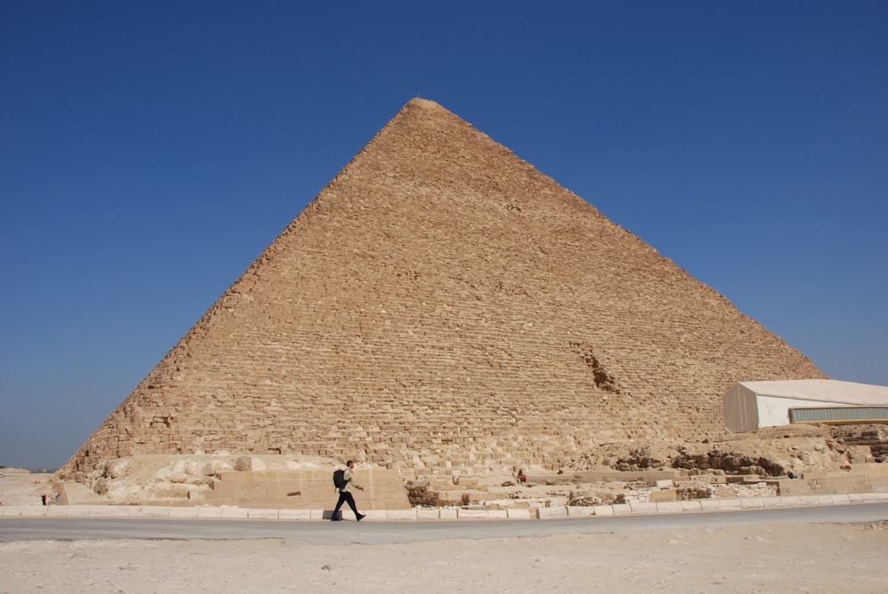 people walking on beach near pyramid during daytime