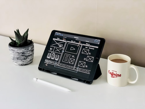 black ipad beside white ceramic mug on white table