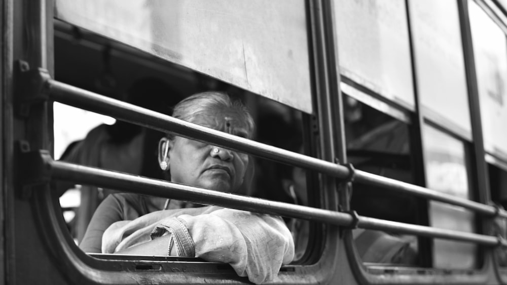 grayscale photo of man in jacket lying on train
