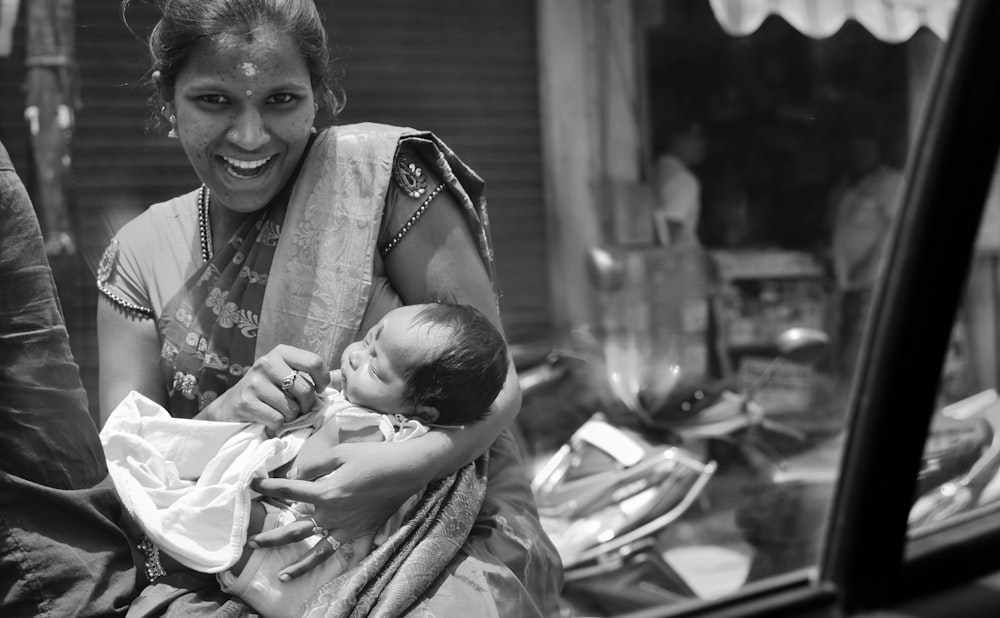 woman carrying baby in grayscale photography