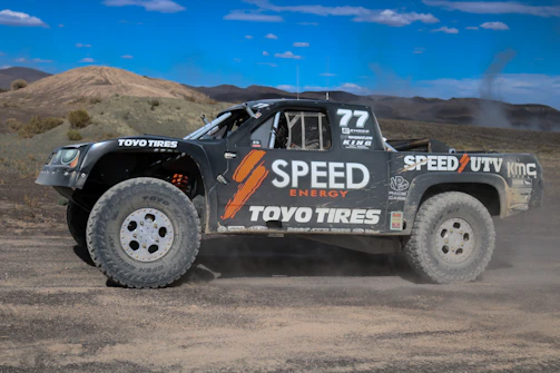 Close-up shot of a race truck kicking up dirt as it navigates rocky terrain.