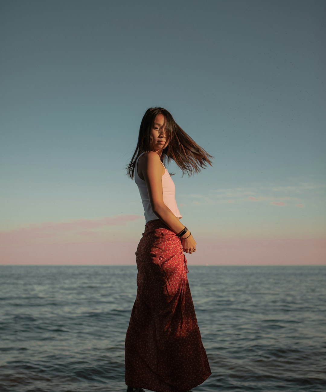 woman in red sleeveless dress standing near body of water during daytime