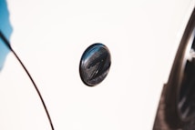 A close-up shot of a car emblem on a white vehicle. The emblem is circular with a dark metallic finish and features a distinctive 'Z' design in the center.
