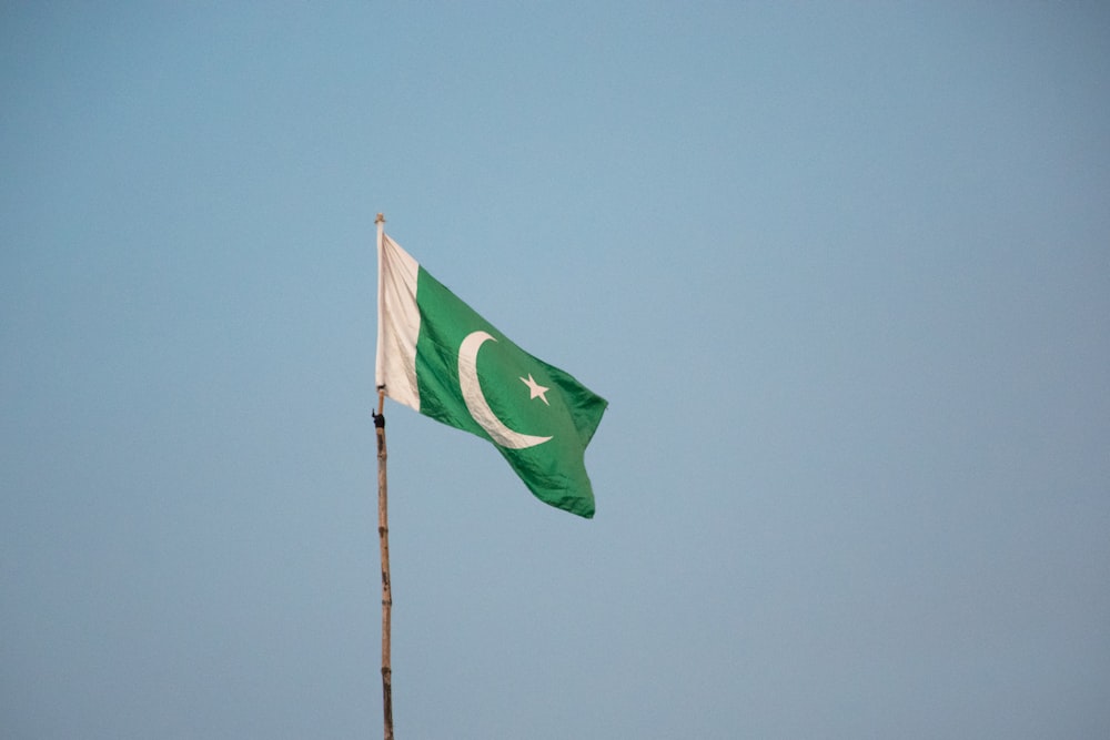 Grüne Flagge auf der Stange unter blauem Himmel tagsüber