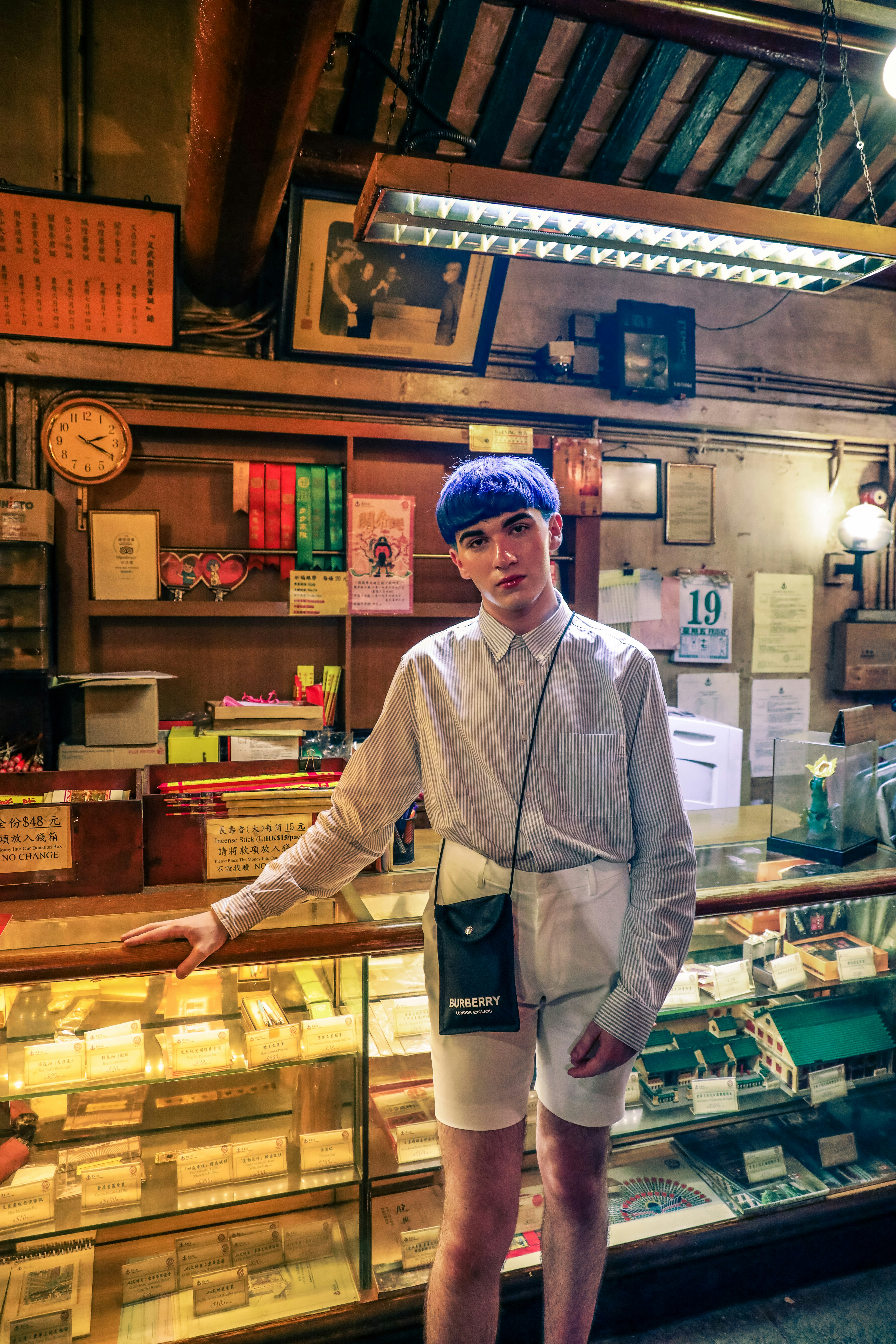 man in white dress shirt standing near brown wooden shelf