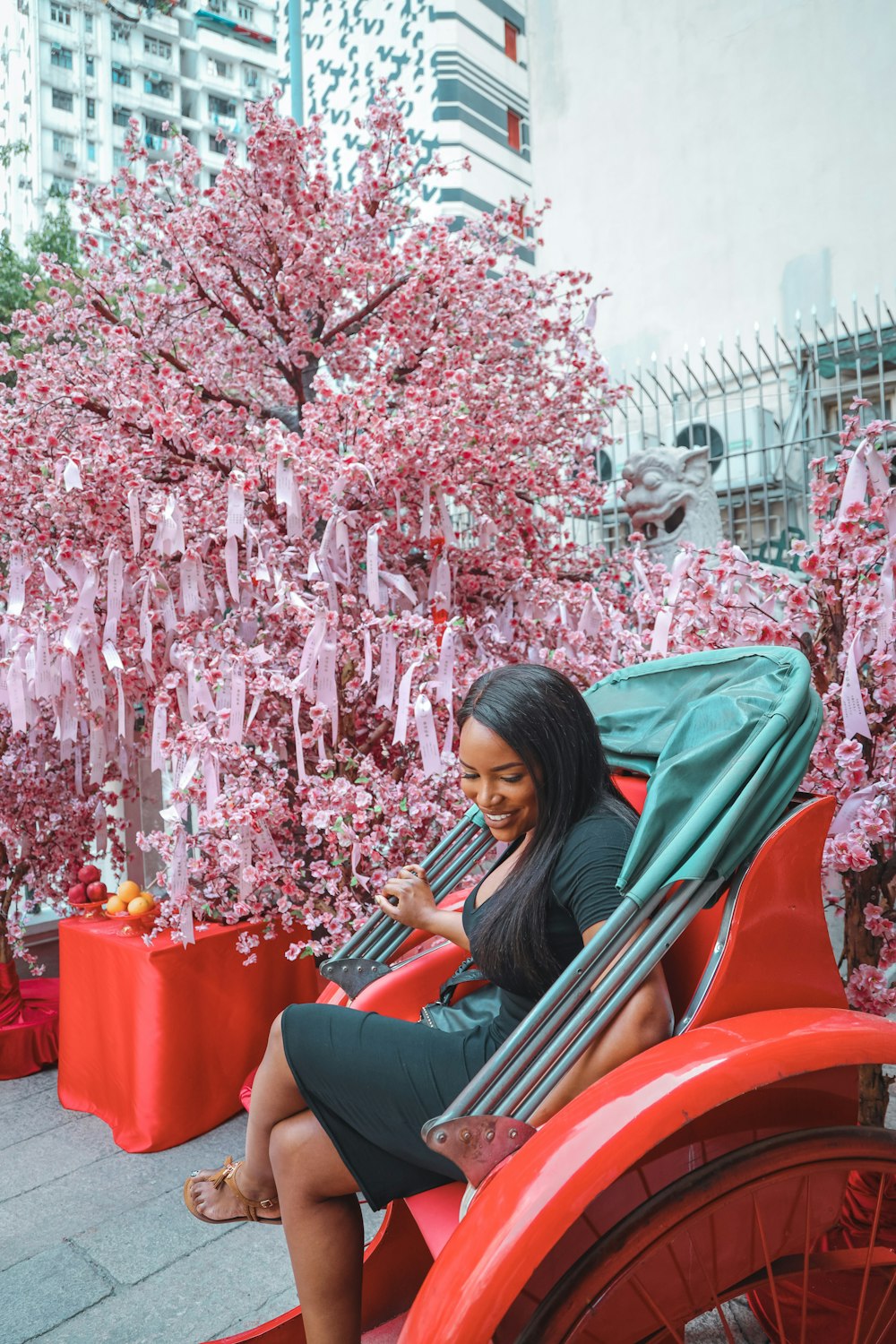 woman in brown long sleeve shirt sitting on red chair under pink leaf tree during daytime