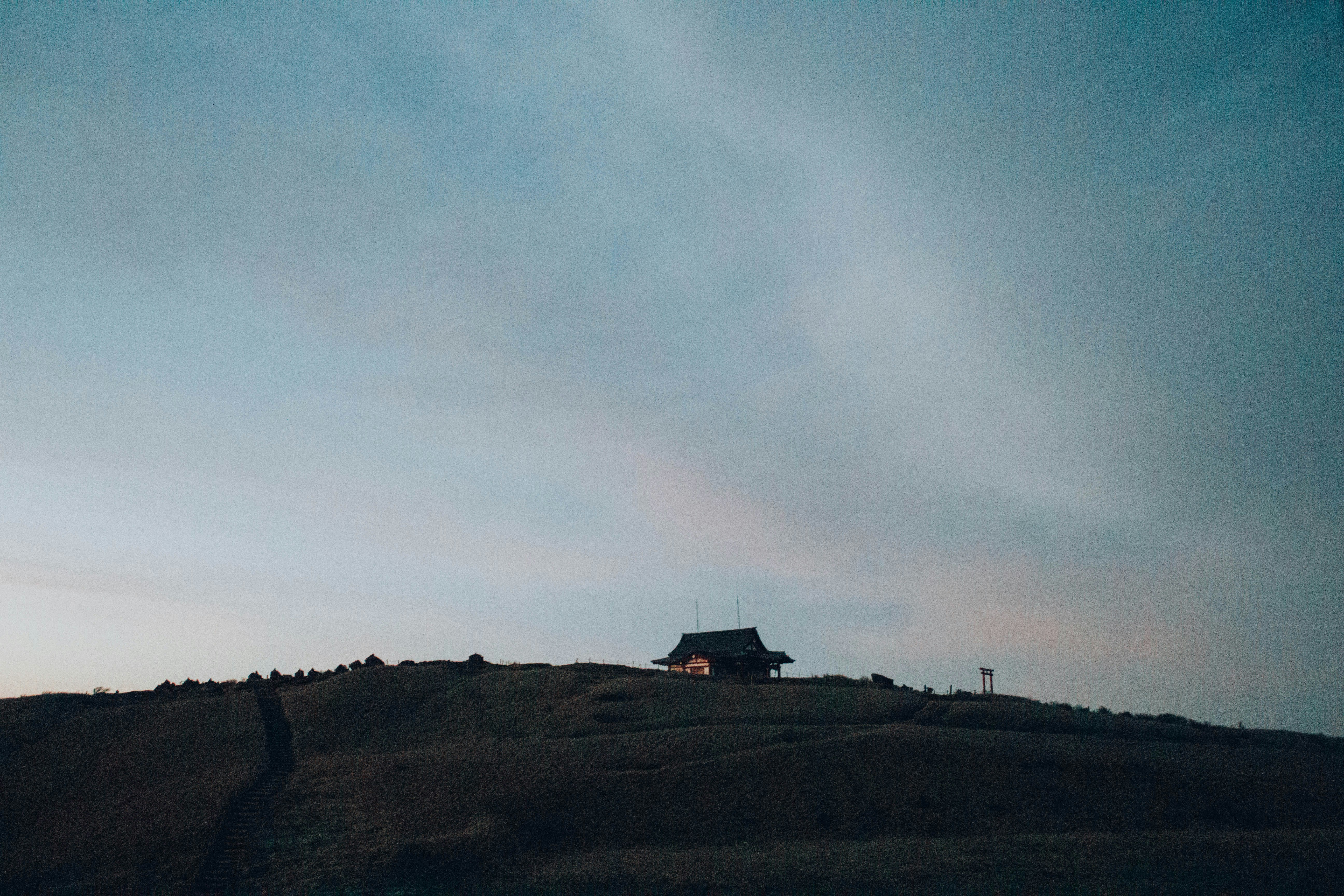 silhouette of house on hill under white clouds during daytime