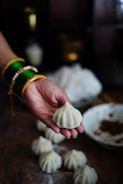 A hand holding a puri dipped in sweet amras, capturing the moment before a bite.