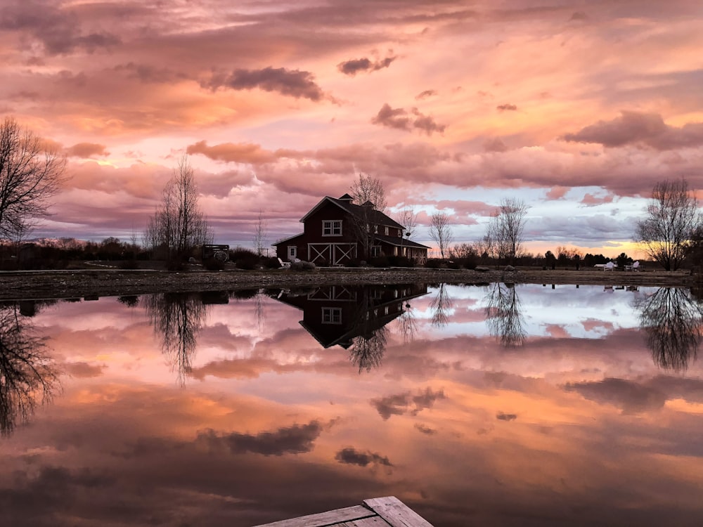 brown wooden house near body of water during sunset