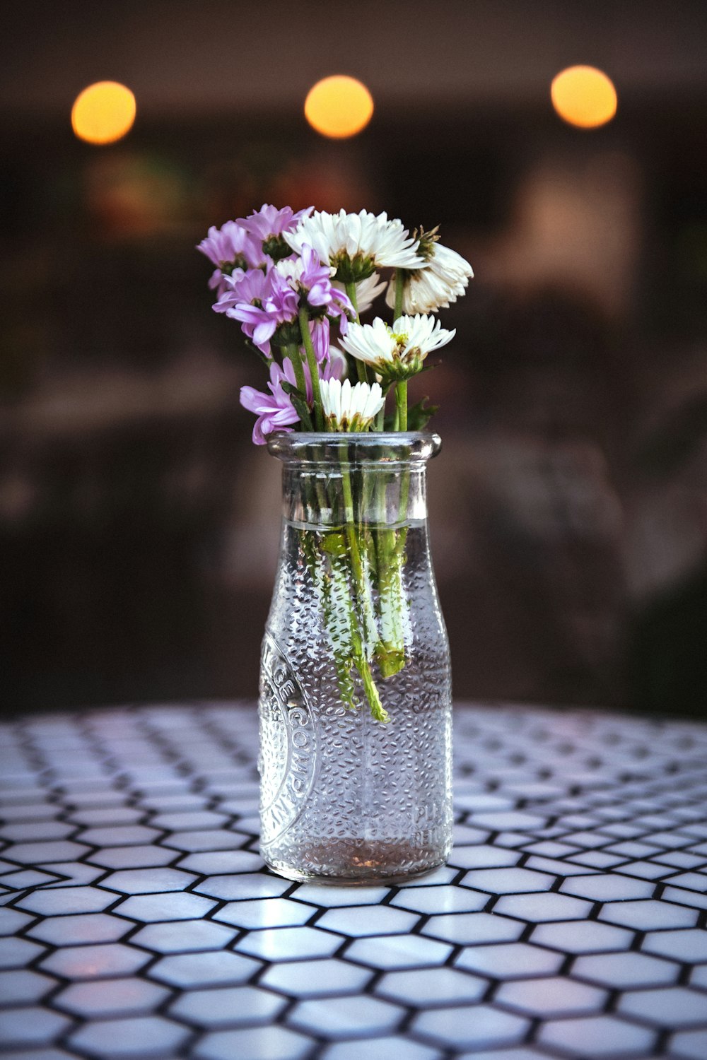 flores blancas y moradas en jarrón de vidrio transparente
