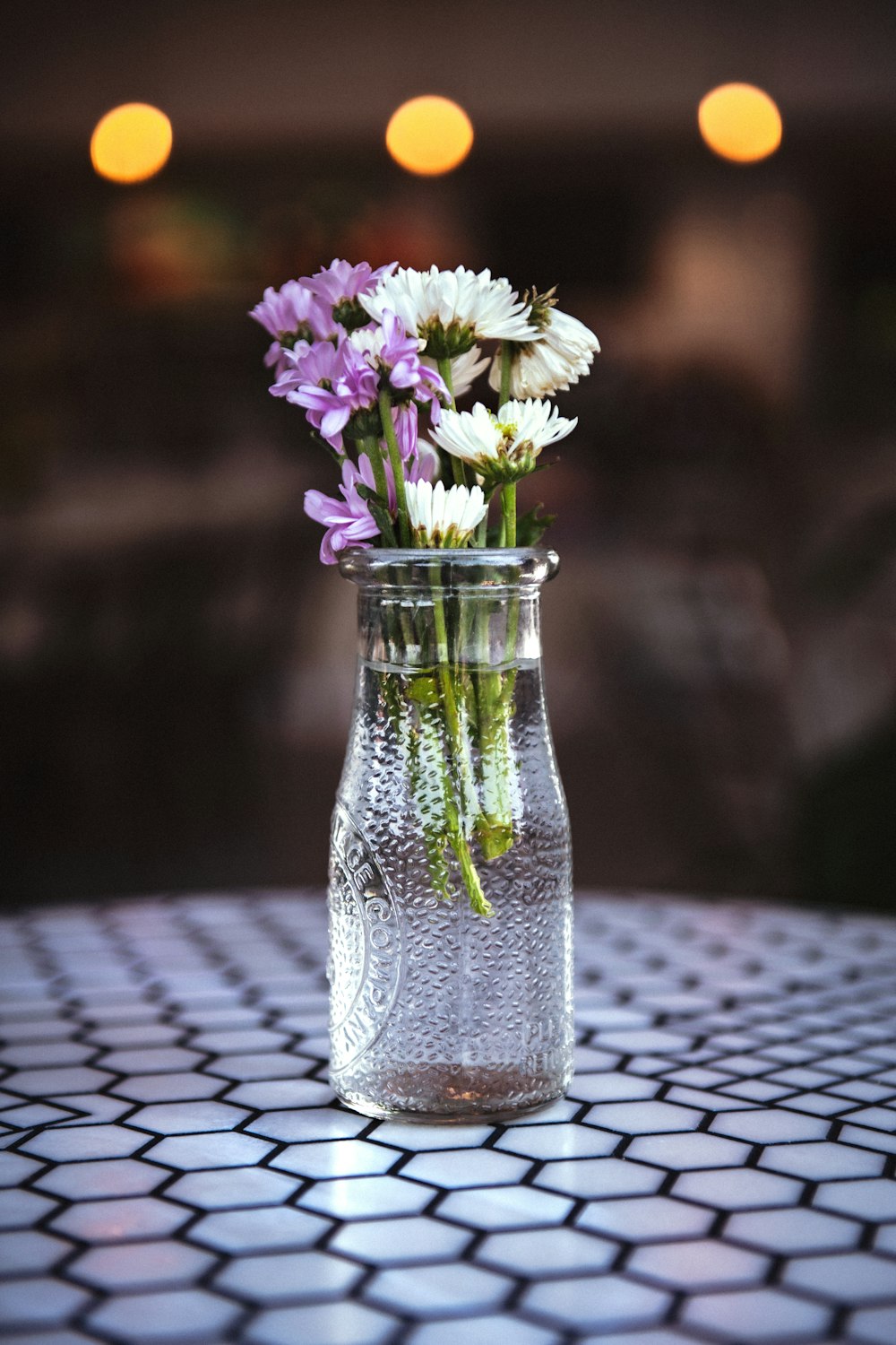 weiße und violette Blumen in klarer Glasvase