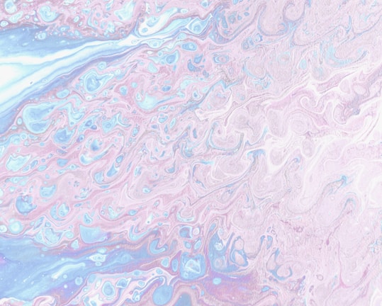 An abstract pattern featuring swirling, marbled designs with a mixture of soft pastel colors including pink, blue, and white. The gentle blending and flowing nature of the pattern gives it a fluid, dream-like appearance.