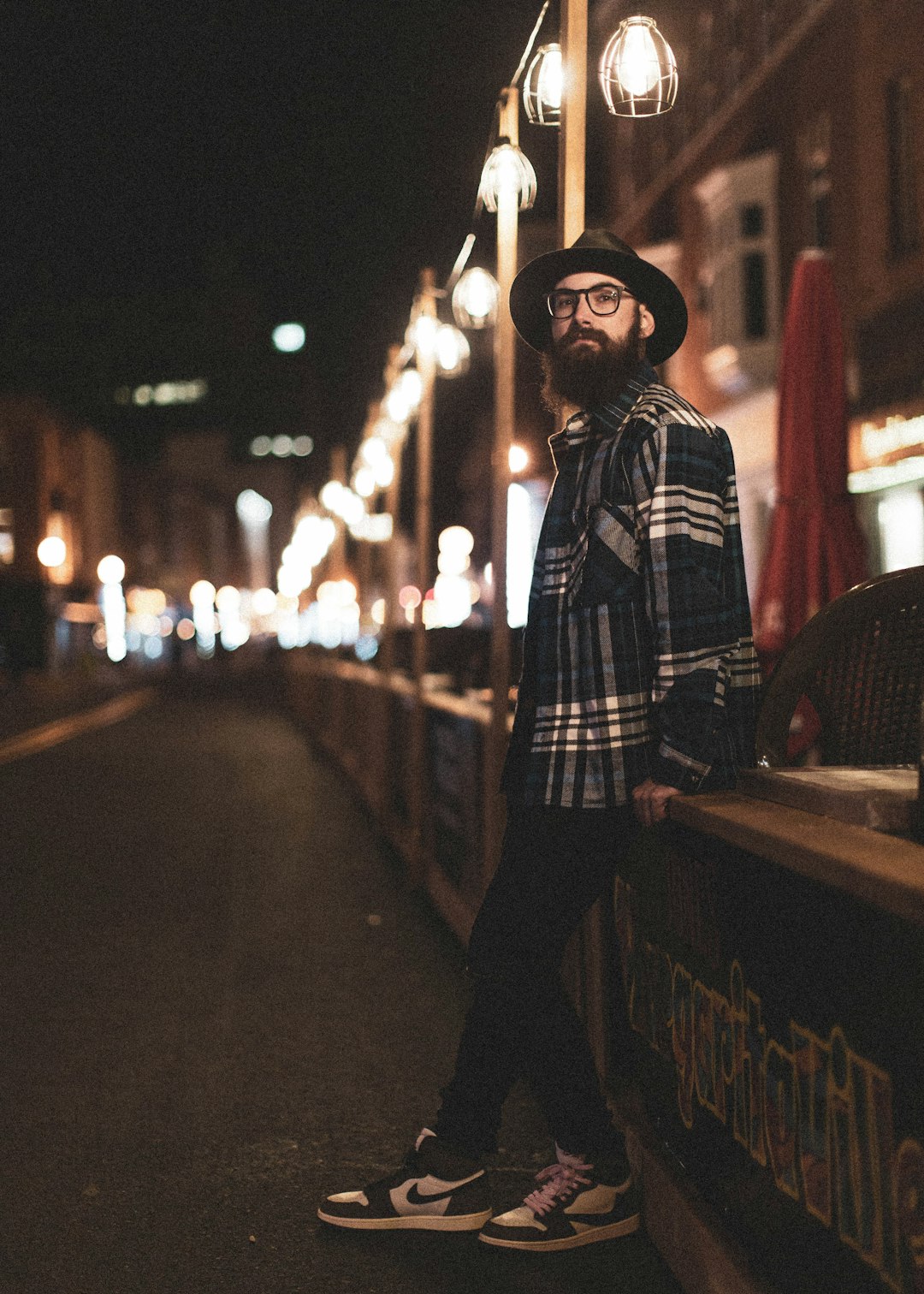 man in black and white plaid dress shirt standing near road during night time