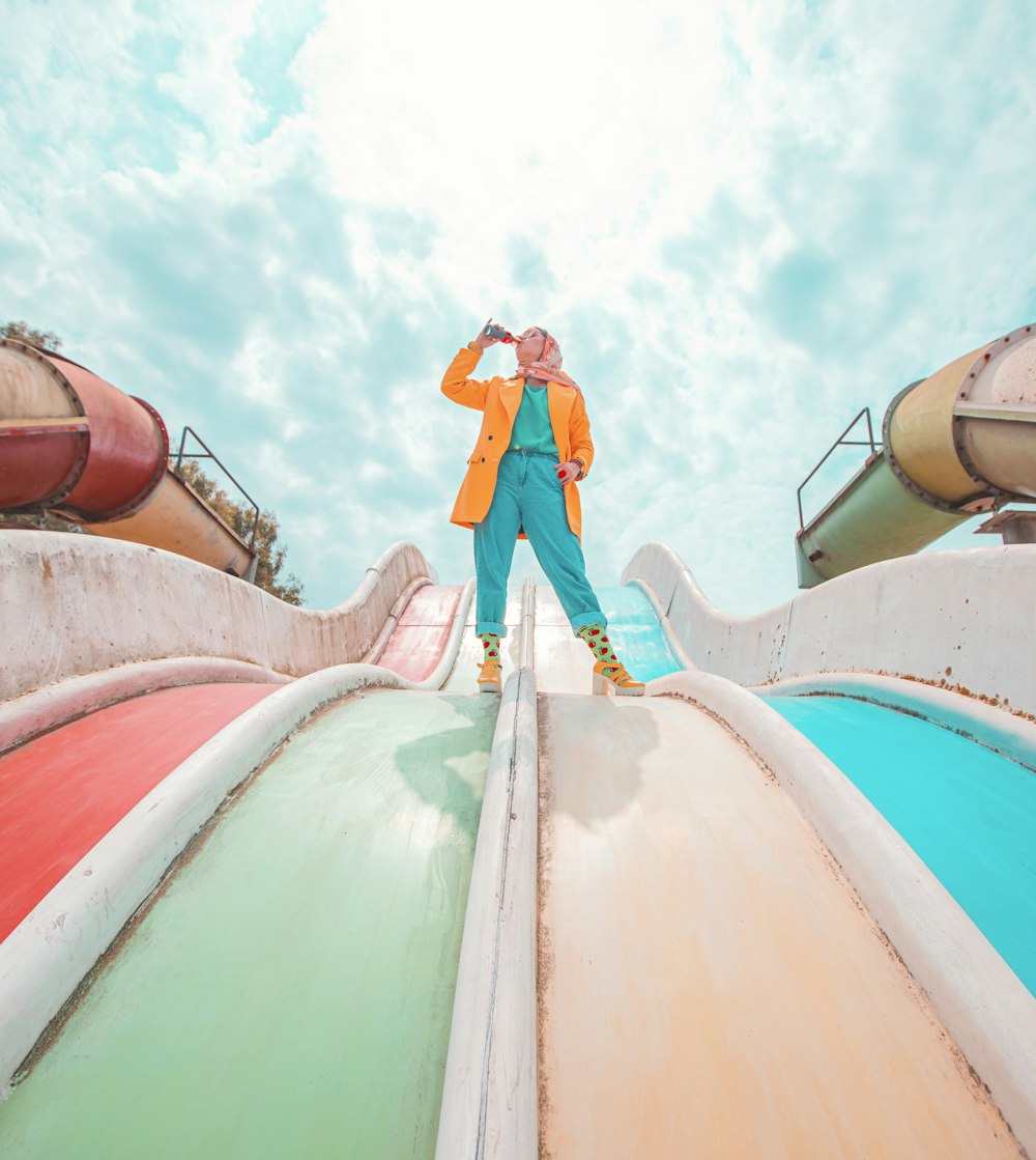 man in blue shirt and pants standing on green and red roof under blue and white