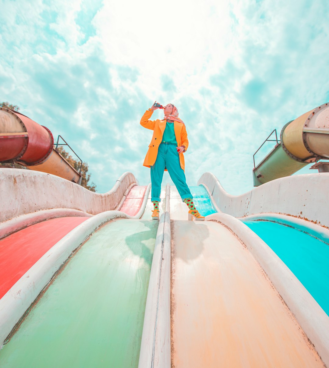 man in blue shirt and pants standing on green and red roof under blue and white