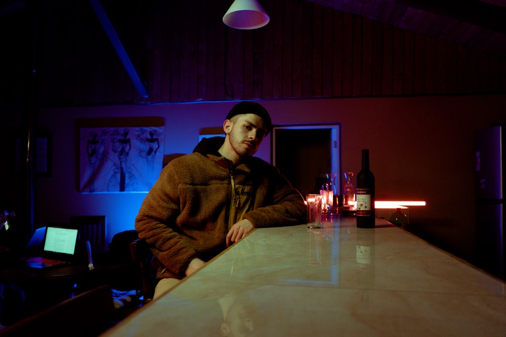 man in brown jacket sitting beside table