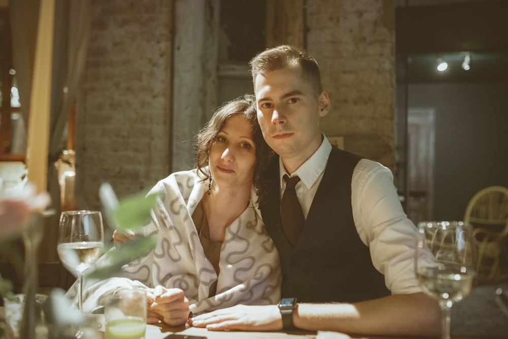 man in black suit jacket smiling beside woman in white and brown floral dress