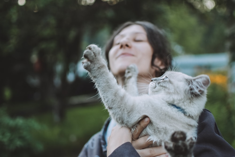 woman in blue and white jacket holding white cat