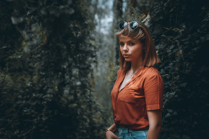 mujer en camisa roja y shorts de mezclilla en el bosque