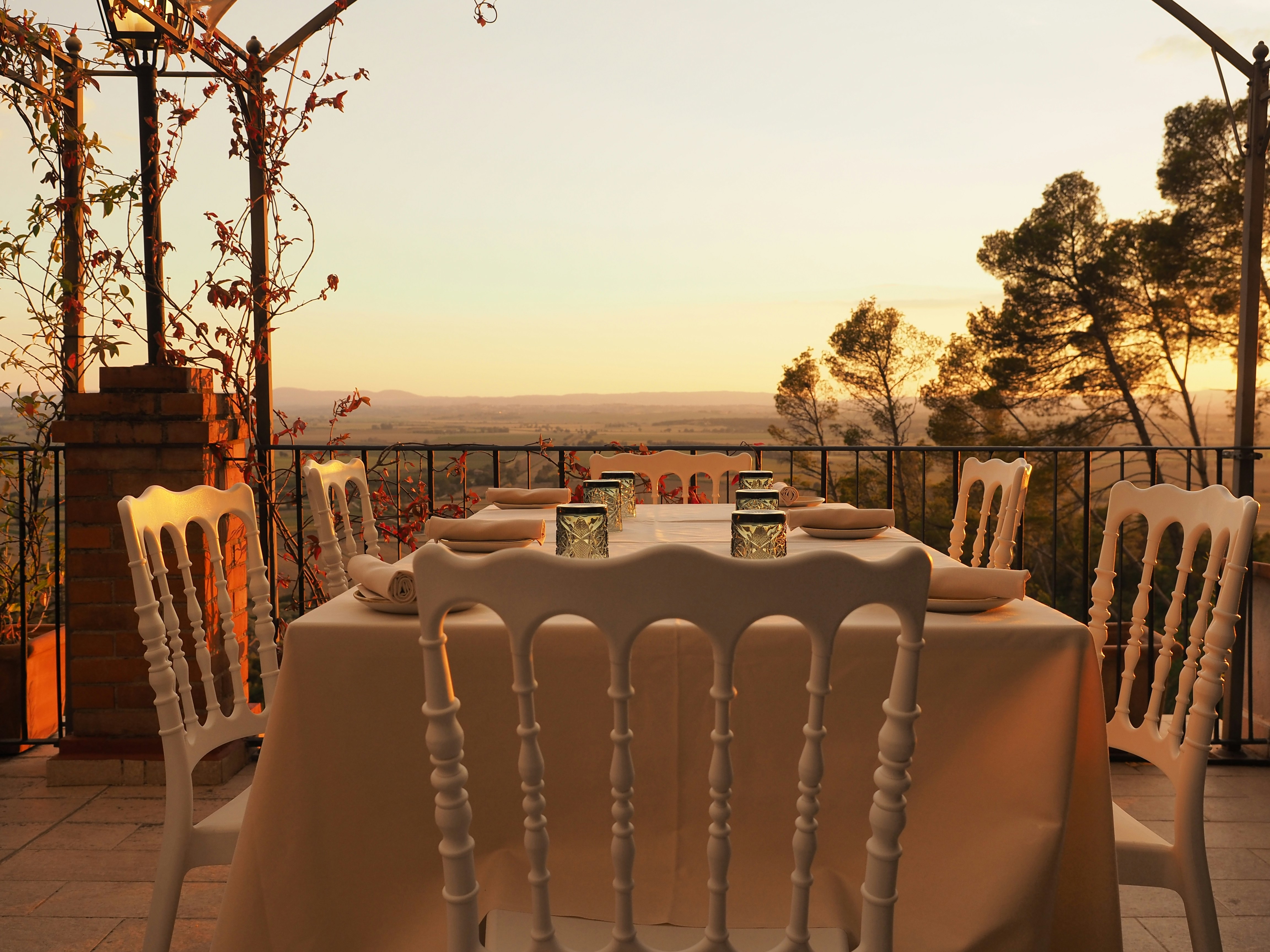 Tavola apparecchiata su una terrazza con vista su un paesaggio verde.