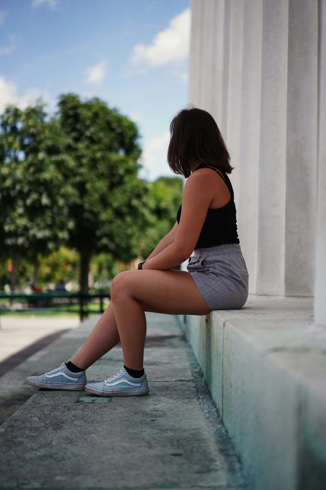 woman in black tank top and white shorts sitting on concrete bench during daytime