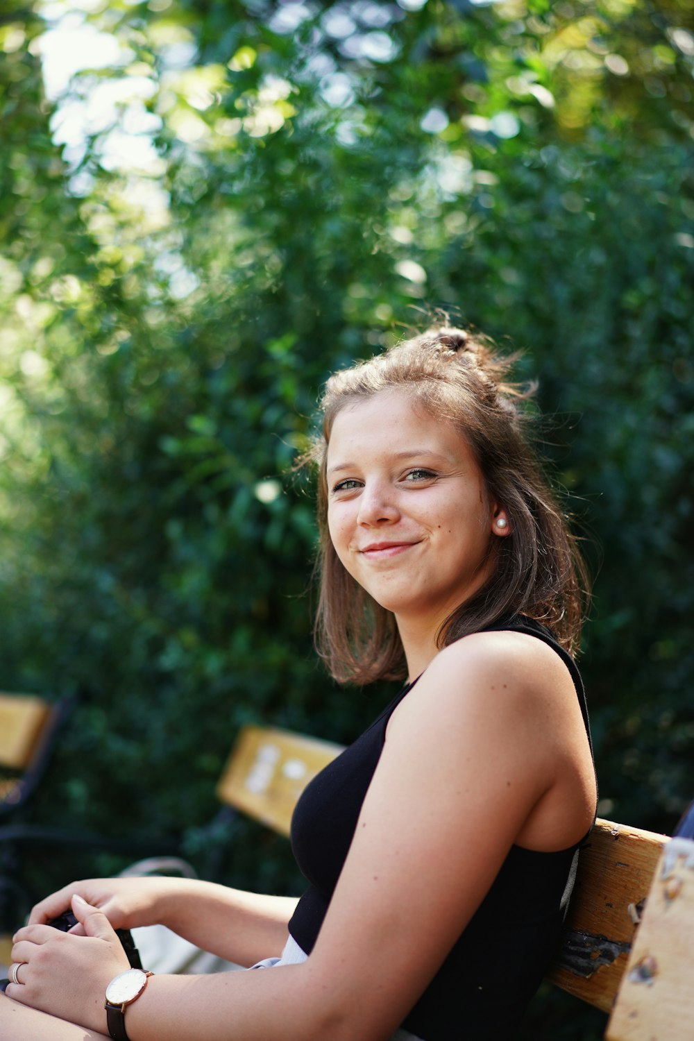 woman in black tank top sitting on brown wooden bench