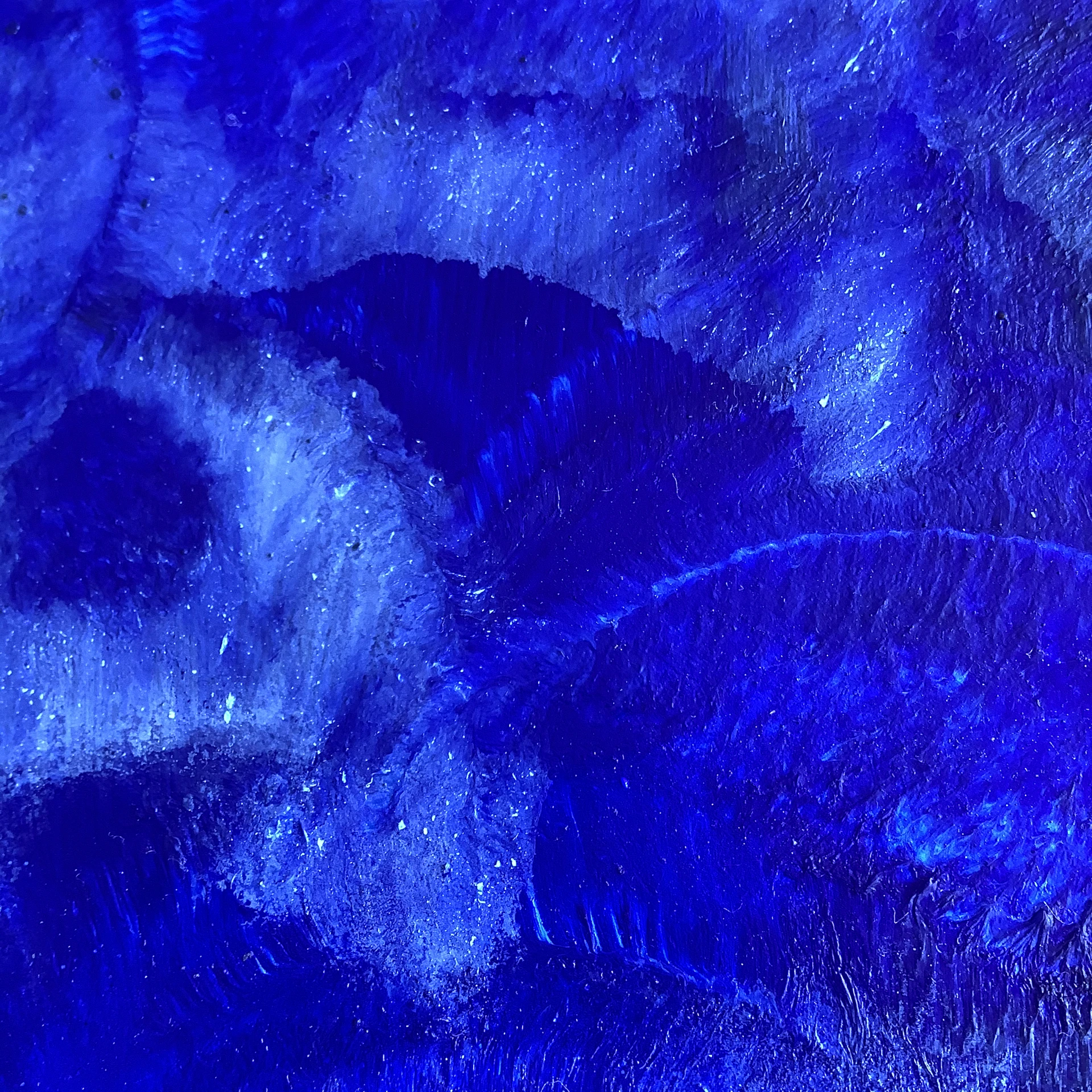 A close-up of a textured abstract painting with deep blues and shimmering gold accents, evoking a mysterious night sky.
