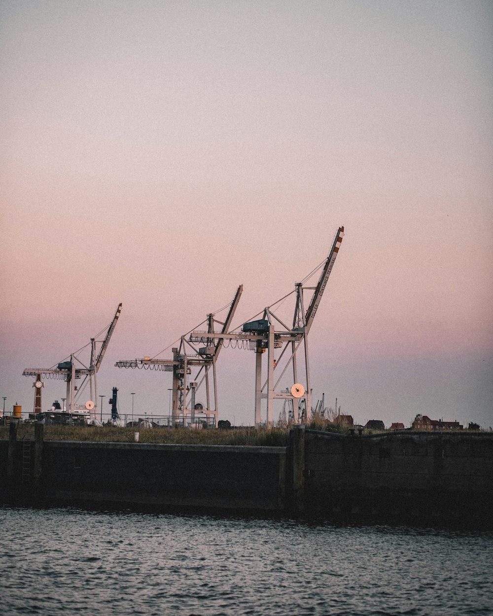 silhouette of crane near body of water during sunset
