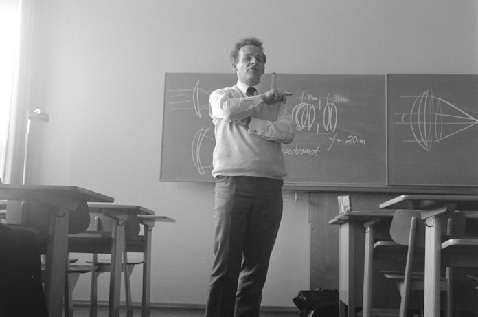 Black and white photo of a teacher in front of a chalkboard, symbolizing the role of educators 