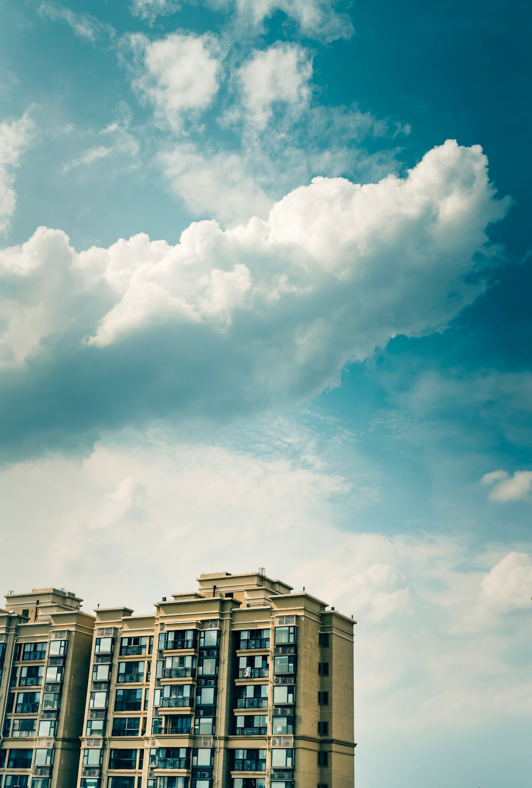white and brown concrete building under white clouds and blue sky during daytime