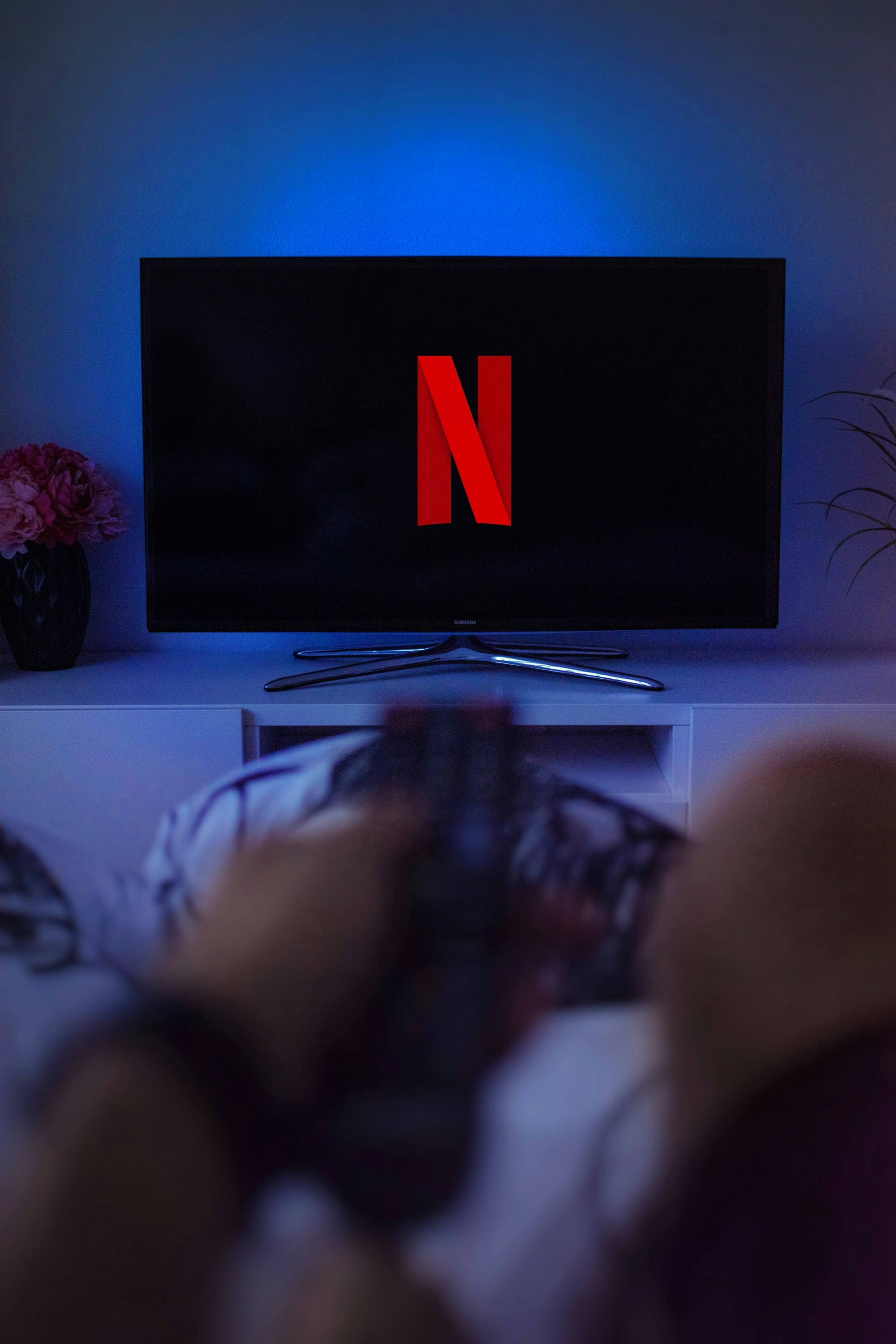 An image of a person watching Netflix on their bed. Netflix apps are built using React.js