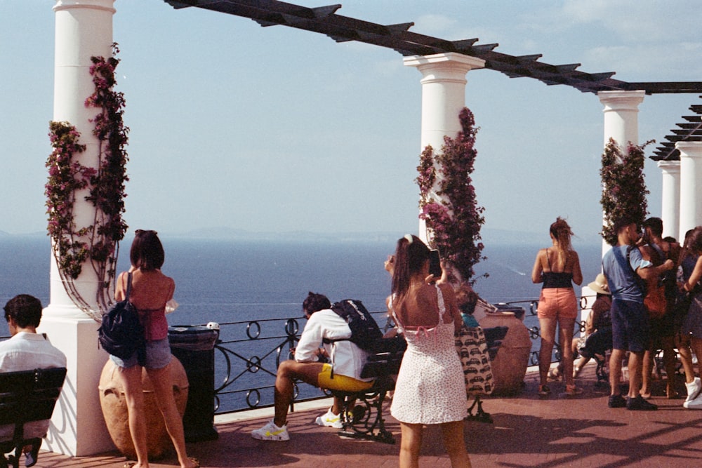 pessoas sentadas em cadeiras de madeira marrom perto do corpo de água durante o dia