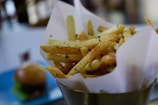 Golden crispy fries sprinkled with seasoning served in a rustic paper cone.