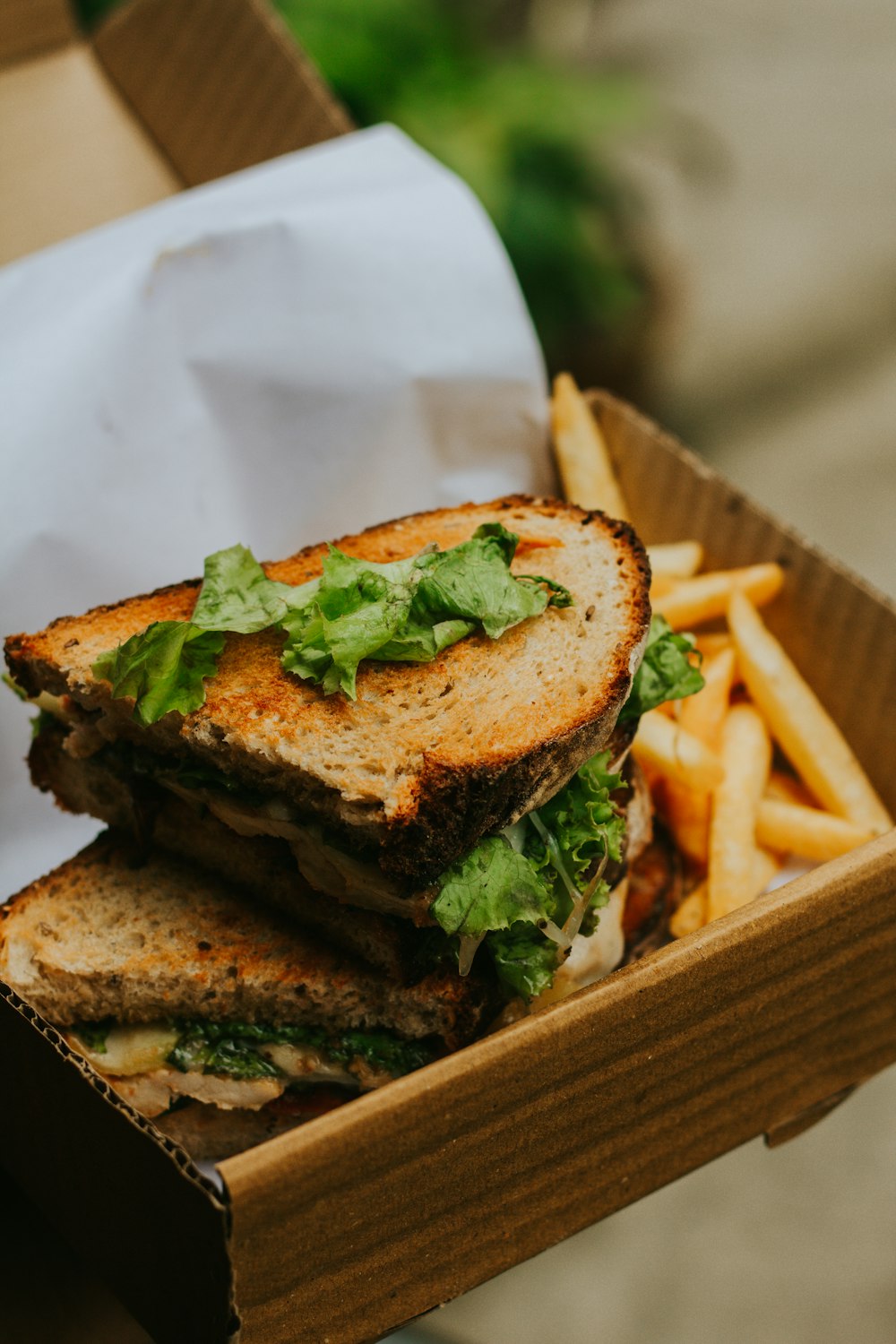 burger with lettuce and fries on brown wooden tray