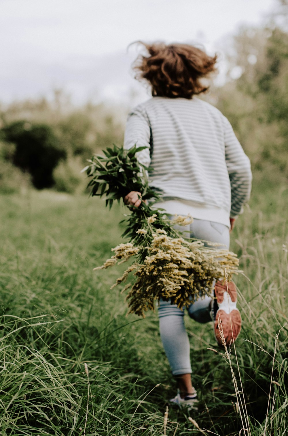 woman in green sweater and blue denim jeans holding brown basket with brown and green grass