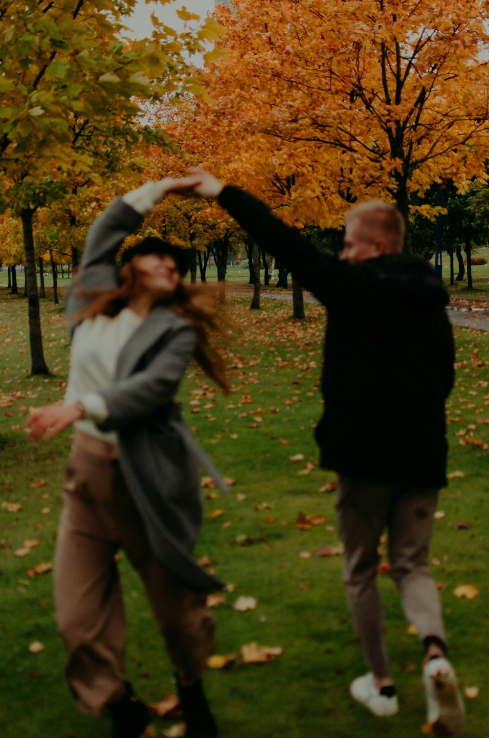 man in black jacket and woman in gray jacket standing on green grass field during daytime