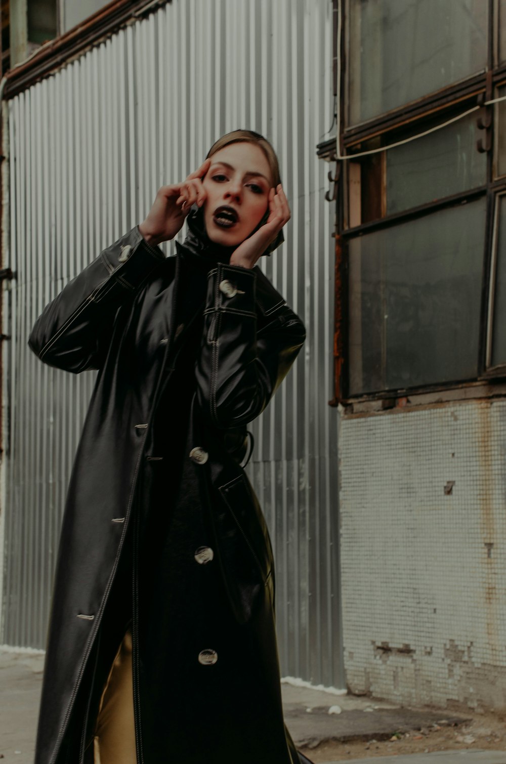 woman in black leather jacket standing near window