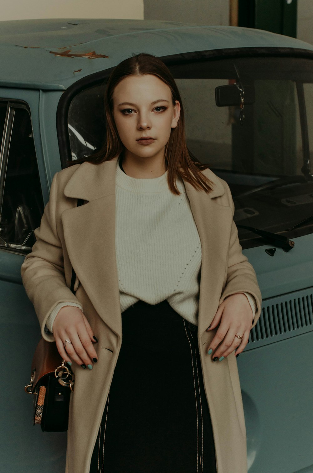 woman in beige coat standing beside car