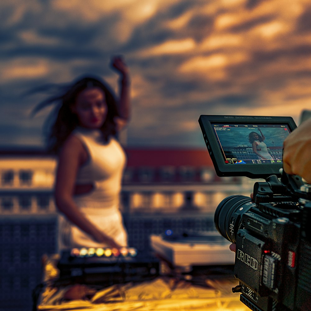 woman in white tank top holding black video camera