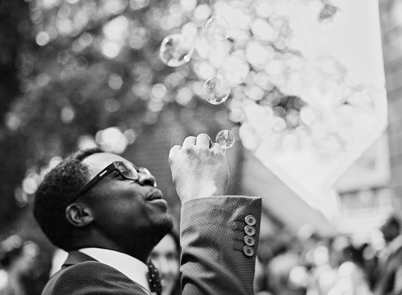 Man in suit blowing soap bubbles for a playful portrait