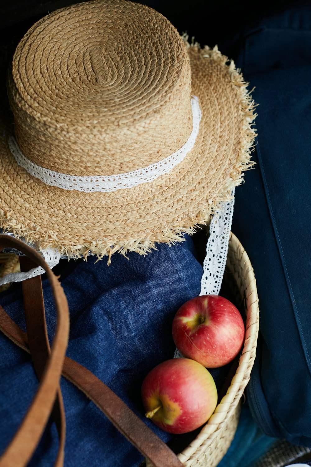 red apple fruit on brown straw hat