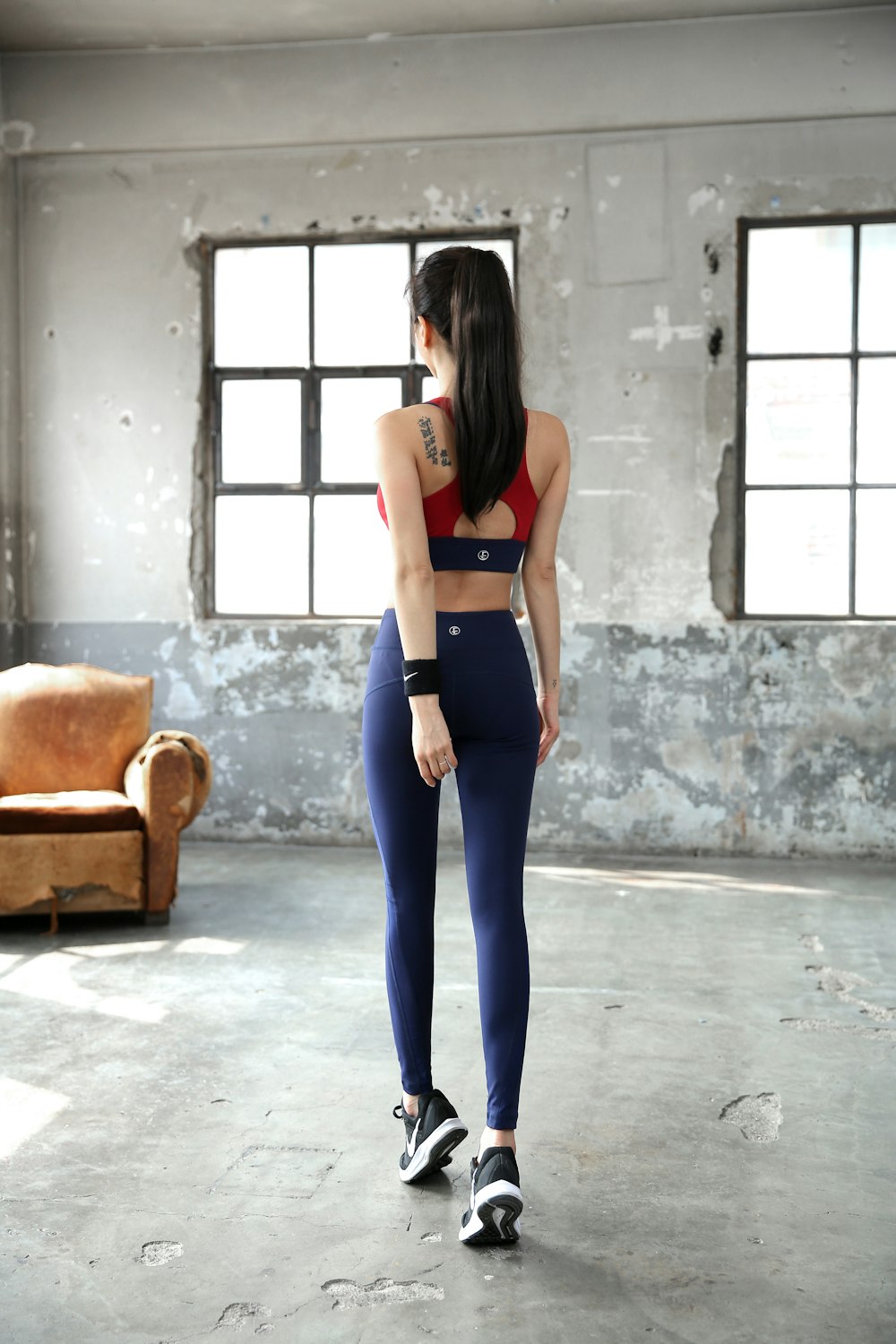 woman in black sports bra and blue denim jeans standing near brown sofa