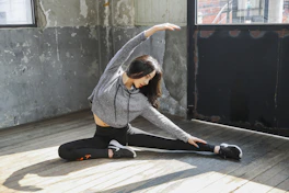 A middle-aged person doing gentle stretching exercises in a bright living room.
