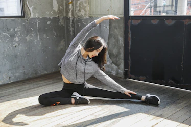 A middle-aged person doing gentle stretching exercises in a bright living room.