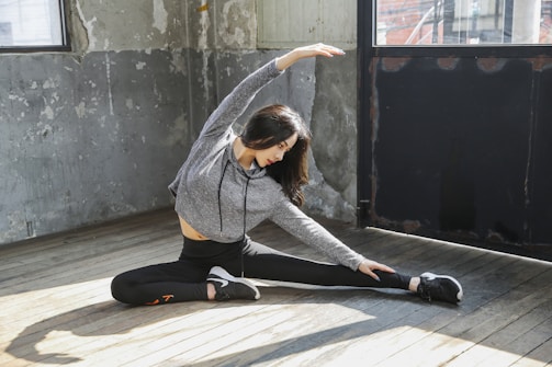 Man stretching hamstrings on floor near couch.
