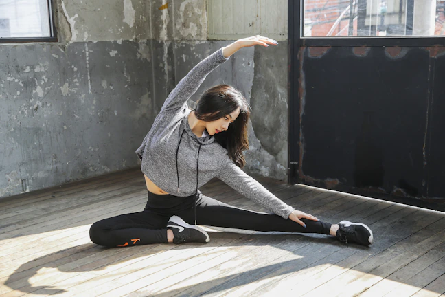A therapist assisting an older man with light stretching exercises in a bright, serene space.