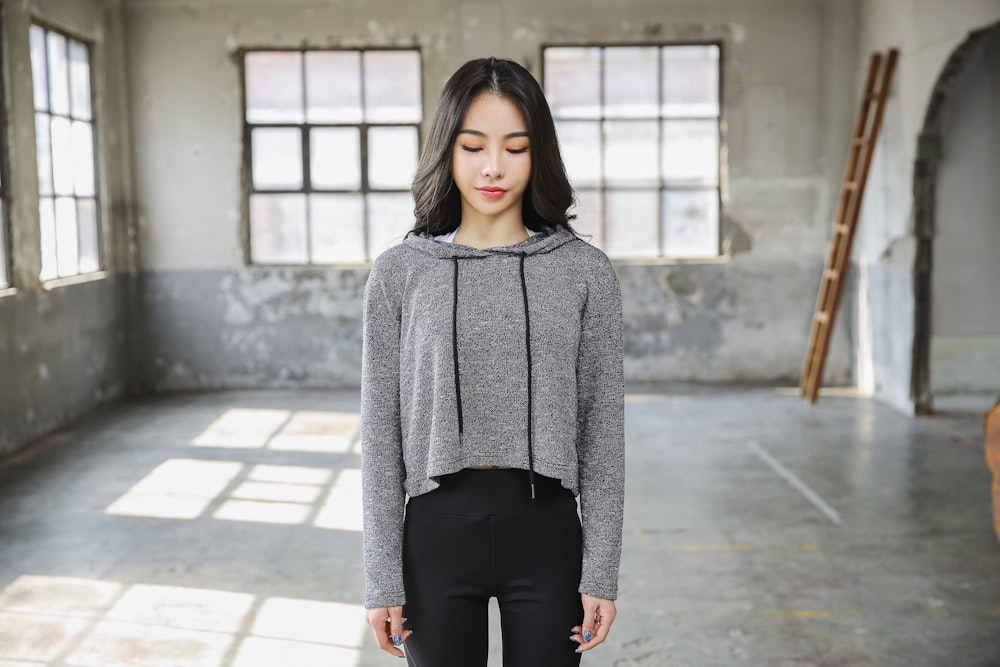 woman in gray sweater and black pants standing on gray concrete floor during daytime