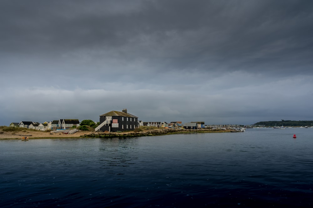 brown and white house near body of water under gray clouds